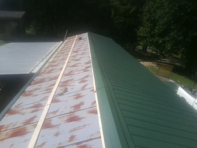 Old rusted panels beside newly installed green metal roofing — Wind Damage Roof Repair by Roofing Brothers in Auburndale