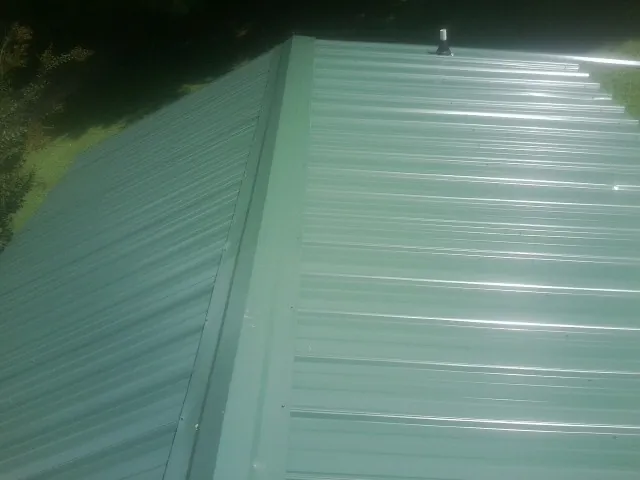 New green metal panels meeting at the ridge of a roof — Flat Roof Repair work by our crew in Auburndale