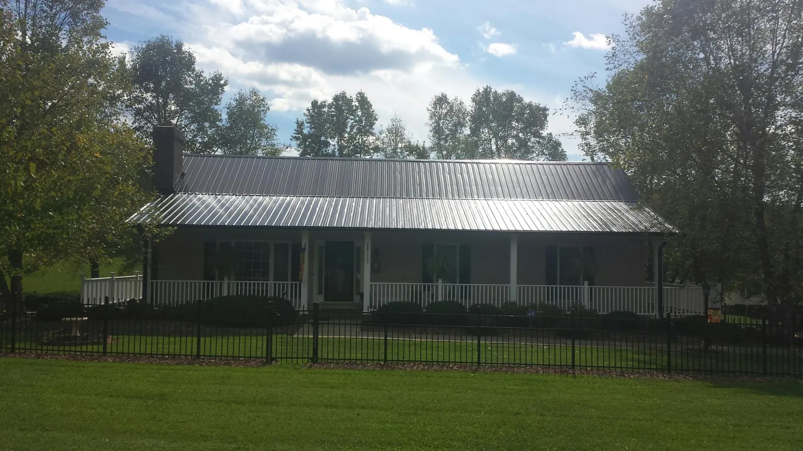 Gray metal roof on a brick ranch with a full width front porch — Gutter Guard Installation work by our crew in Auburndale
